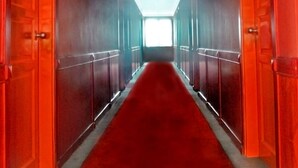 A corridor with red doors and a red carpet leading to a bright end. - Plaza Hotel Harco Mangga Dua (Jakarta)