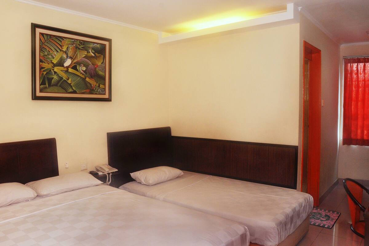 A hotel room with two beds, a painting on the wall, and a red curtain.
