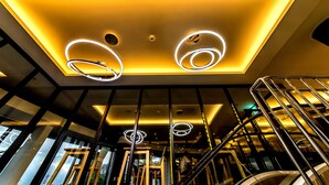 Un interior moderno con una escalera, techo iluminado y vistas al exterior.