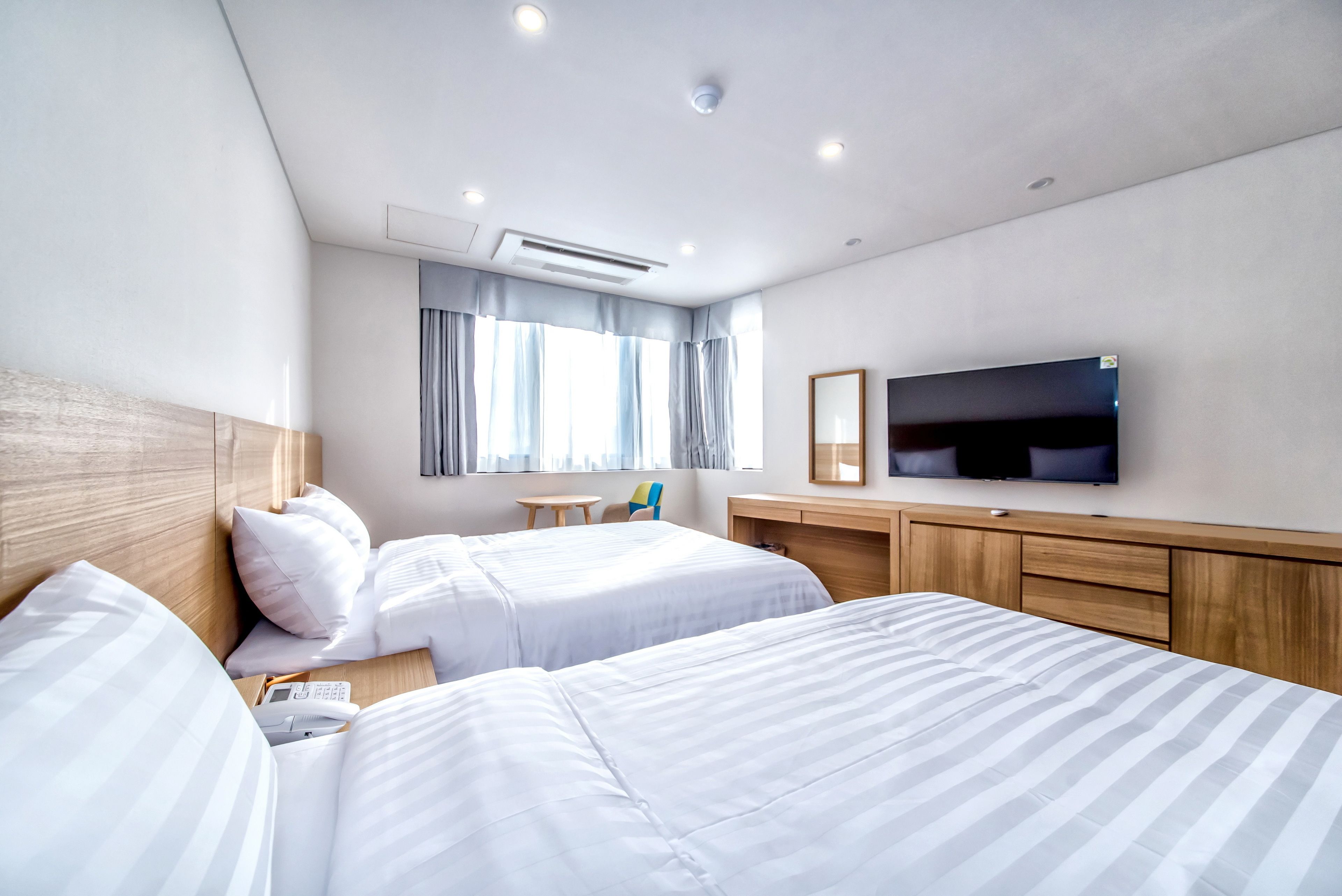 Une chambre d’hôtel avec deux lits, une télévision, un bureau et une fenêtre avec des rideaux.
