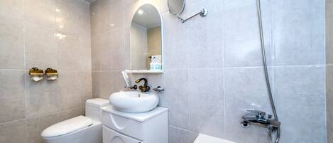 A modern bathroom with a toilet, sink, and bathtub.