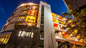 Un hotel moderno con fachada curva, varios balcones e iluminación de señalización.