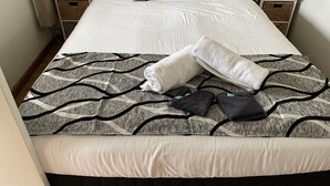 A neatly made bed with a patterned bedspread, white pillows, and a rolled towel on the bed. - Forster and Wallis Lake Motel (Forster)