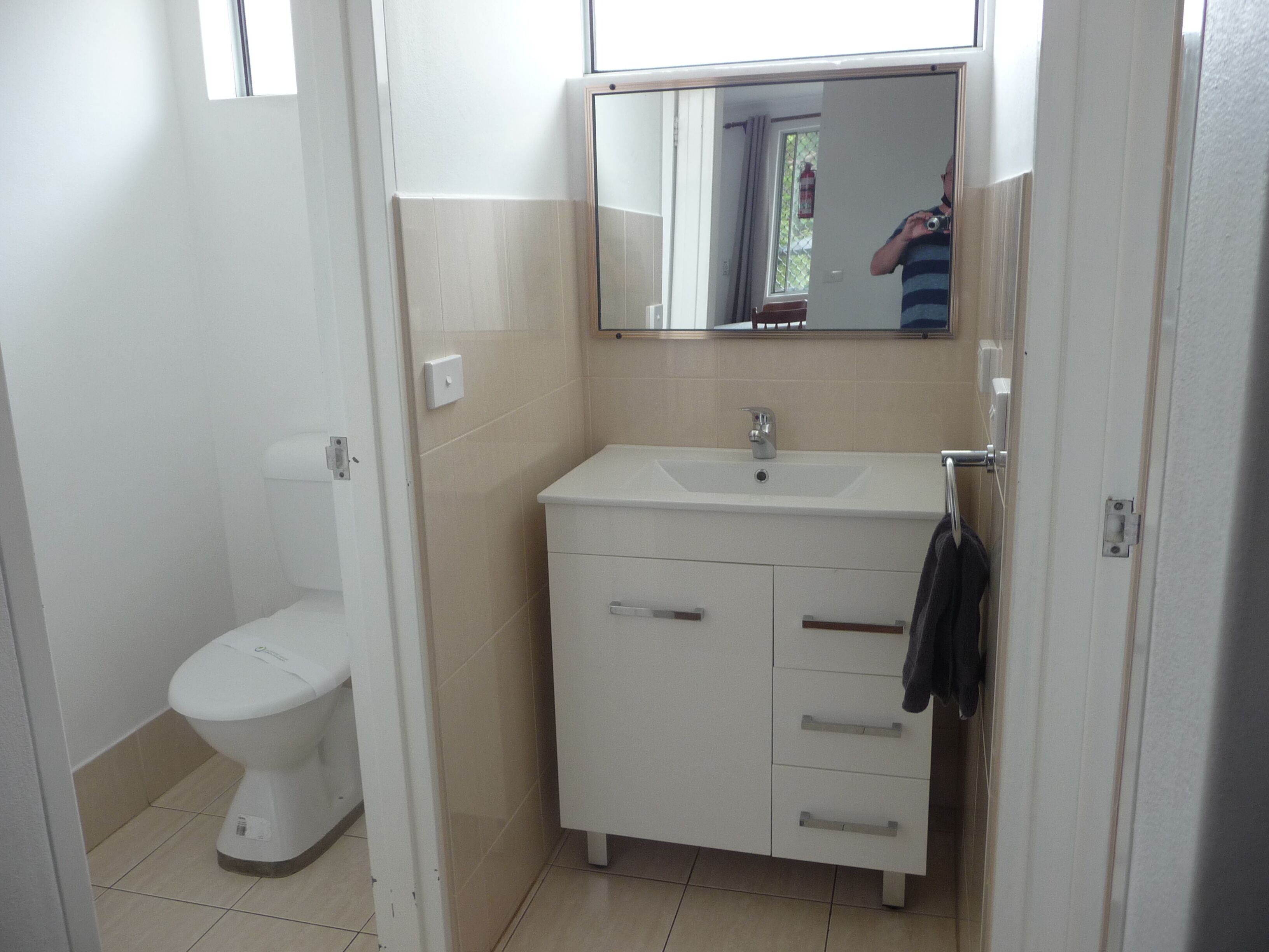Un baño con inodoro, lavamanos y espejo.