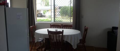 Un área de comedor con mesa y sillas, una ventana que ofrece vistas al exterior y un refrigerador.