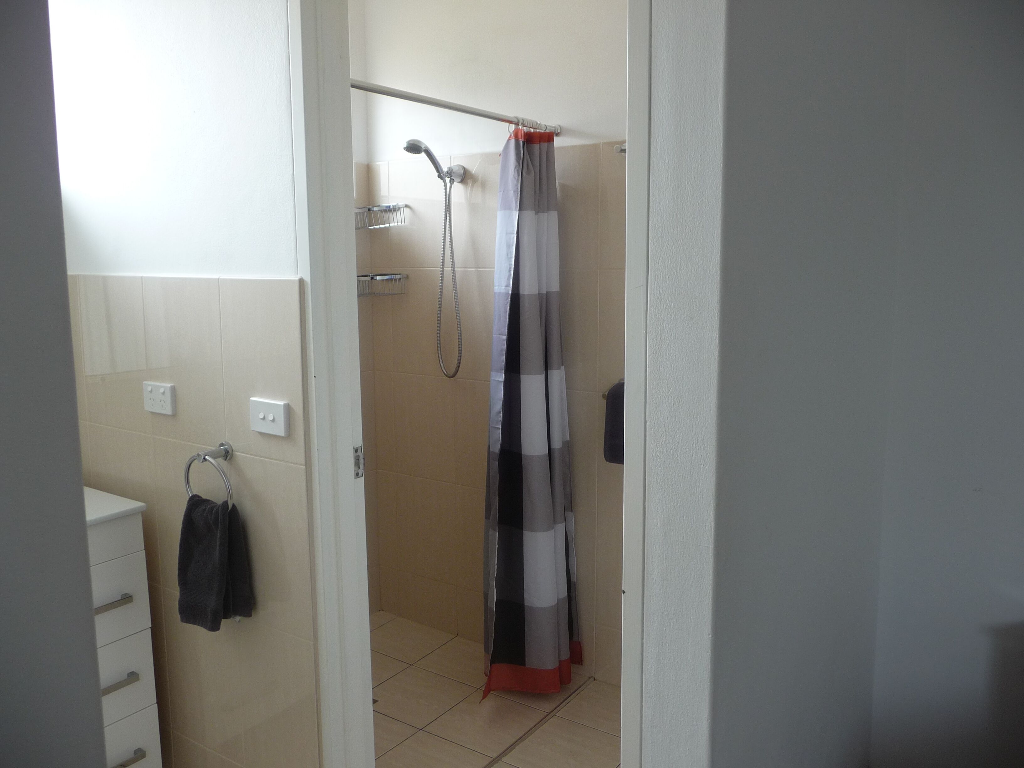 Un baño con ducha, toallero y retrete.