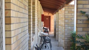 A covered outdoor seating area with brick walls, tables, and chairs. - Forster and Wallis Lake Motel (Forster)