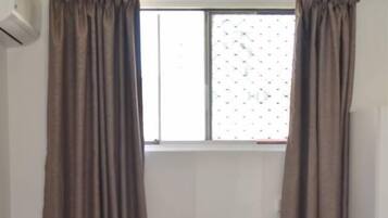 Ein rotes Sofa mit einem gemusterten Kissen, eine hölzerne Bank und ein Fenster mit Vorhängen.