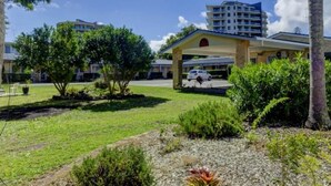 A hotel with a covered parking area, a building with multiple floors, and a clear sky. - Forster and Wallis Lake Motel (Forster)