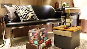 A modern living room with a leather sofa, a small wooden coffee table, and vintage suitcases. - Hotel B7 Journey (TAIPEI)
