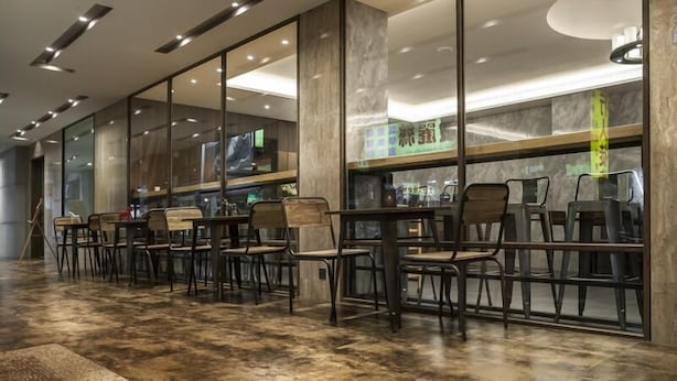 A modern restaurant with a long counter and multiple chairs, large windows, and a polished stone floor. - Hotel B7 Journey (TAIPEI)