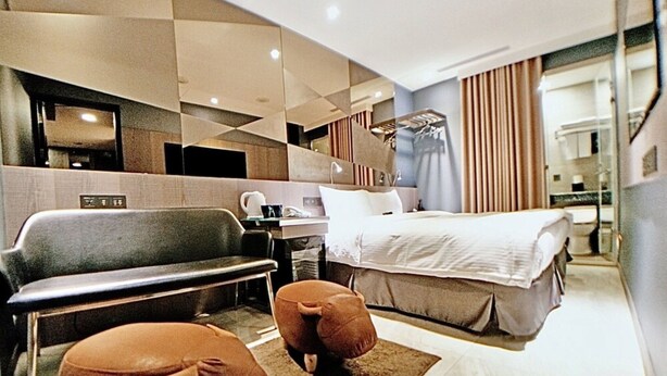 A modern hotel room with a bed, a sofa, two ottomans, a desk, and a mirror. - Beauty Hotels Taipei Hotel B7 Journey (Taipei)