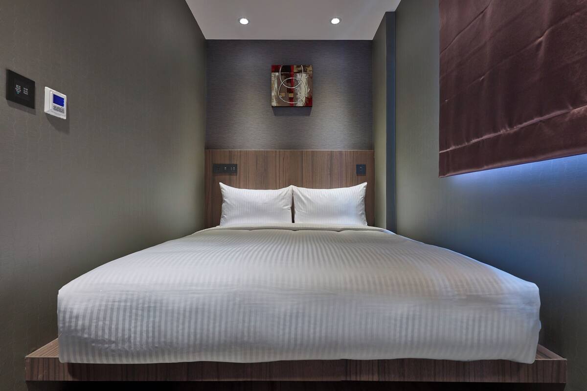 A neatly made bed with white linens in a modern hotel room.