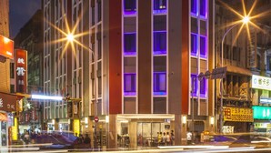 A multi-story hotel with a modern facade, illuminated windows, and a ground-level entrance. - Beauty Hotels Taipei Hotel B7 Journey (Taipei)