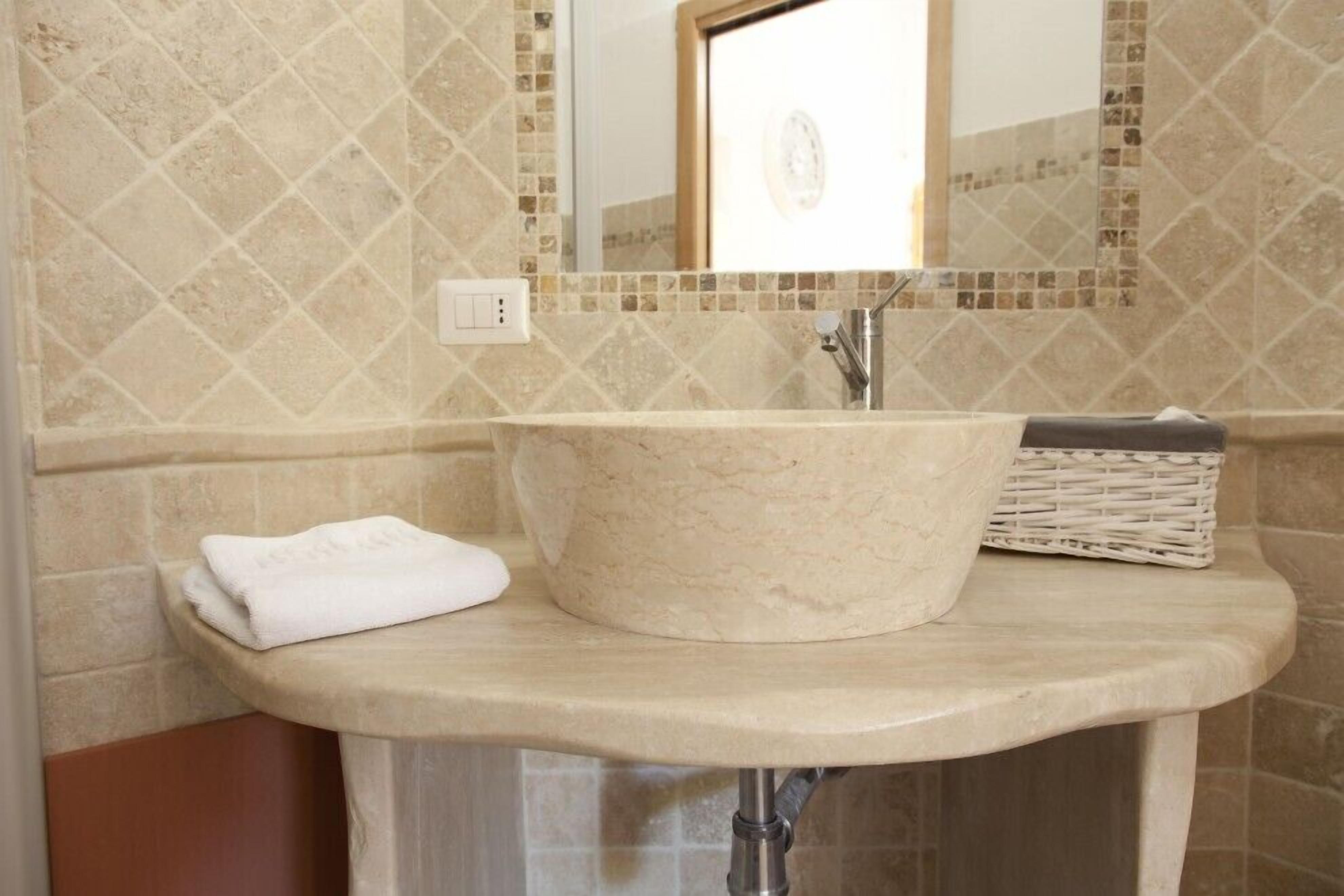 Un baño con lavamanos de mármol, un espejo y una toalla en la encimera.