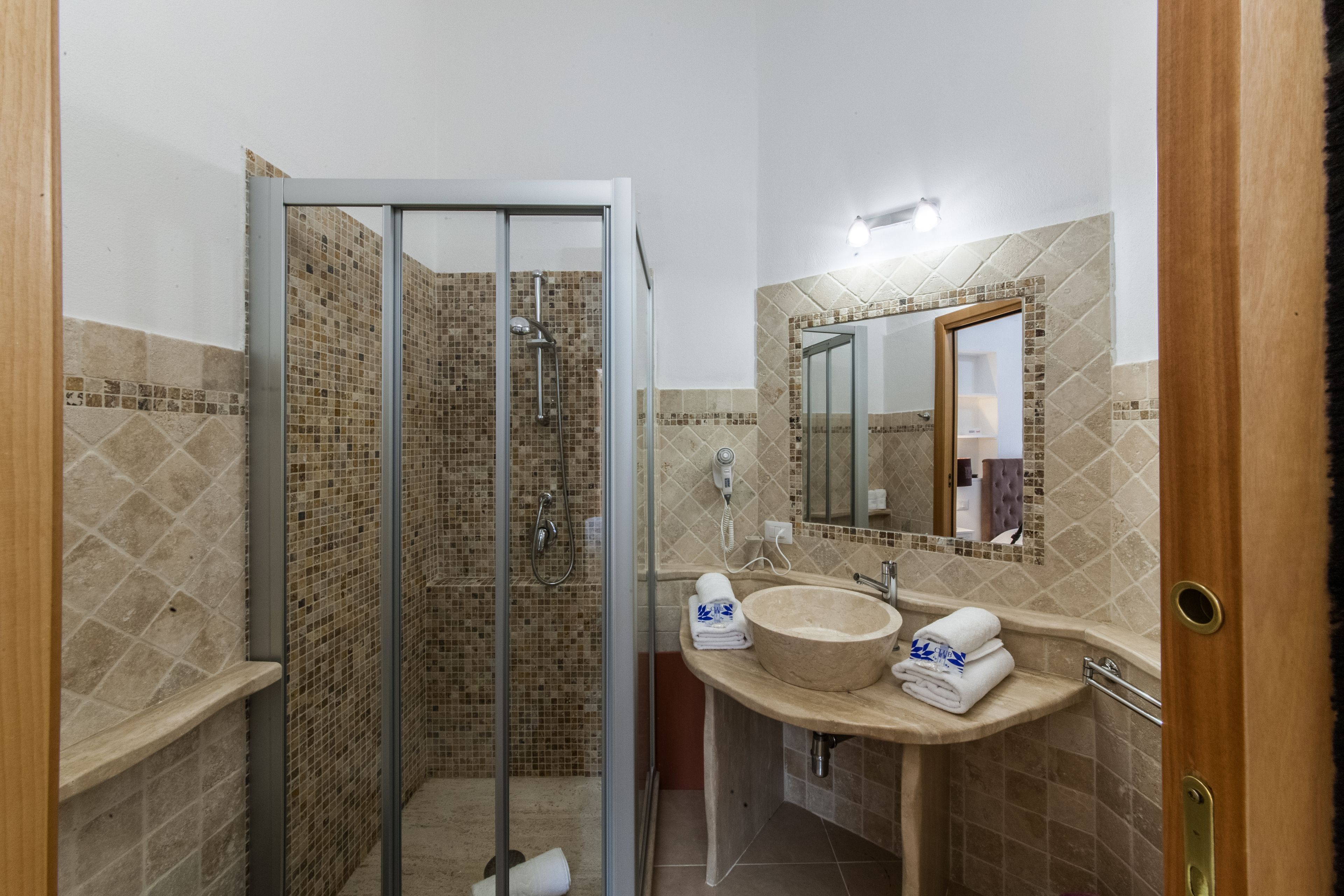 Un bagno con doccia vetrocamera, lavabo con specchio e porta asciugamani.