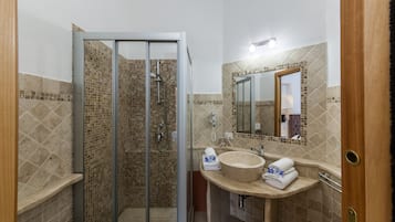 Un bagno con doccia vetrocamera, lavabo con specchio e porta asciugamani.