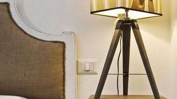 Ein Bett mit Kopfteil, ein Nachttisch mit Lampe und einem gestreiften Lampenschirm sowie eine kleine Schublade.