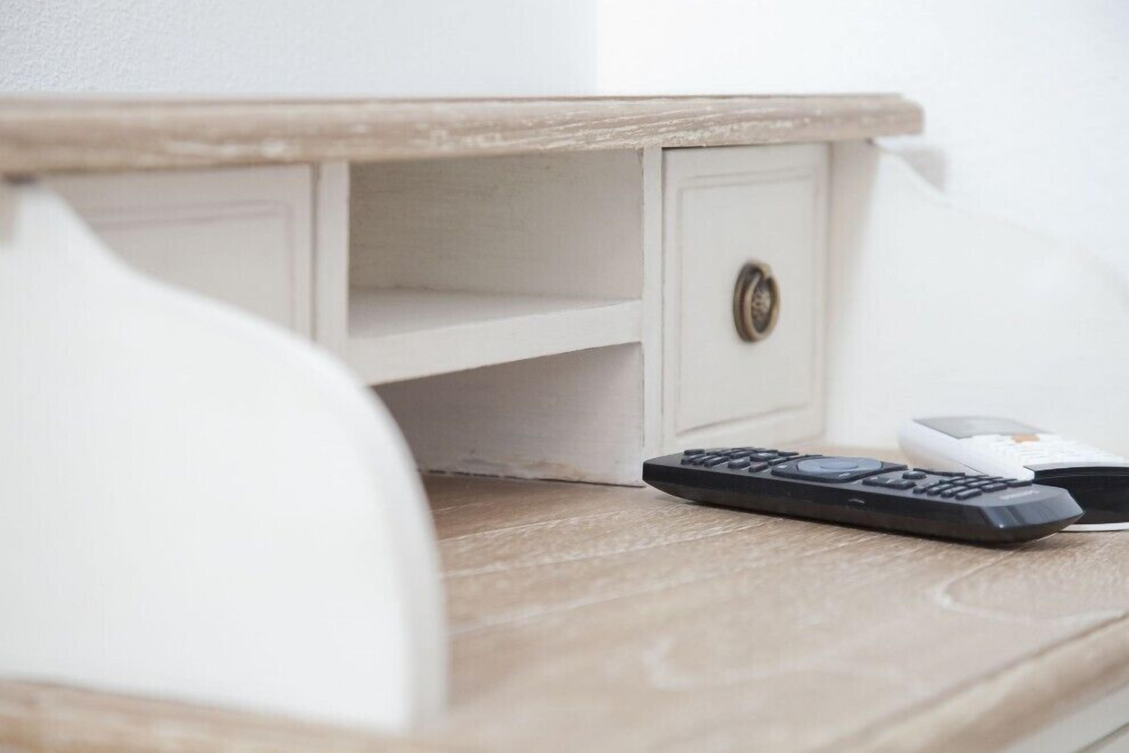 Une table en bois sur laquelle se trouvent une télécommande et un appareil blanc.