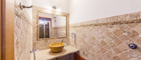A bathroom with a large mirror, a beige sink, and a shower.