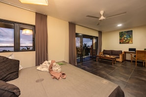A hotel room with a bed, a sofa, a dining table, and a view of the outdoors. - Happy Days Guest House (La Gaulette)