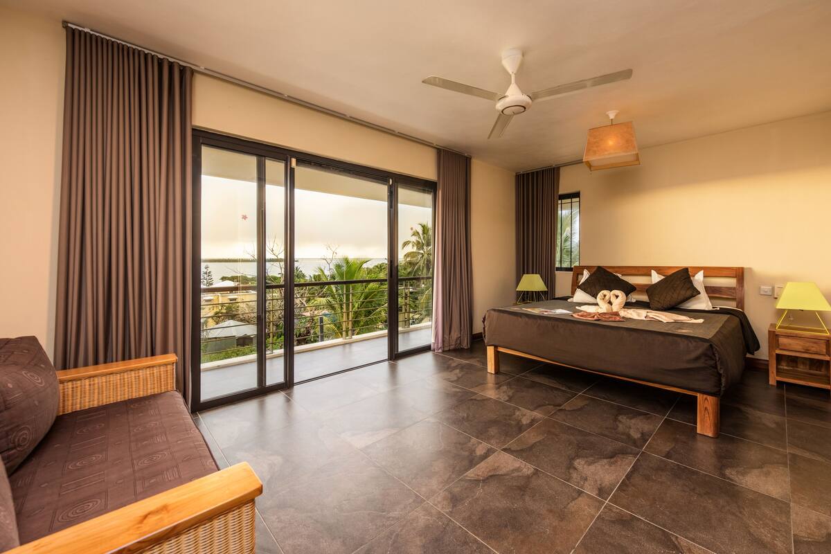 Ein geräumiges Schlafzimmer mit einem großen Bett, einem Schlafsofa und einem Balkon mit Aussicht.