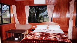 Una habitación de madera con una cama, una mesita y una ventana con cortinas.