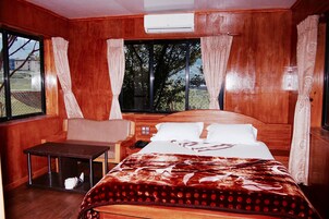 Una habitación de madera con una cama, una mesita y una ventana con cortinas.