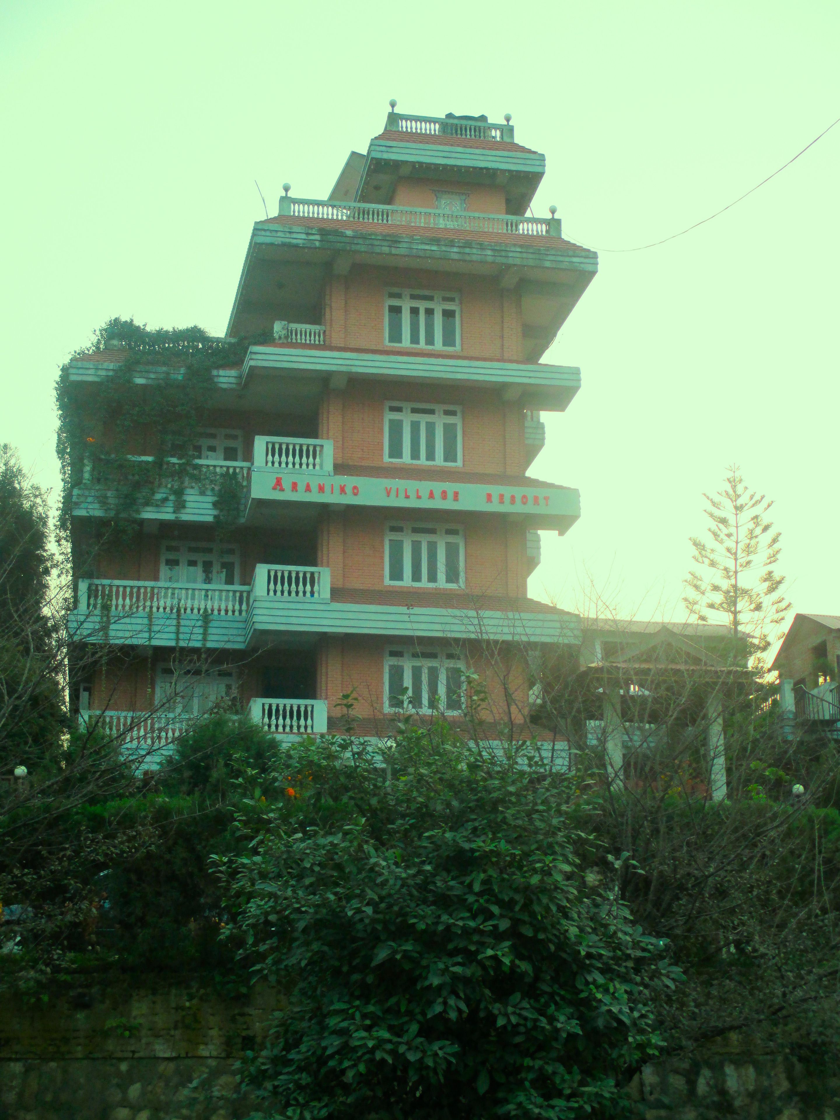 A multi-story building with balconies and a sign that reads "Karaniko Village Resort".