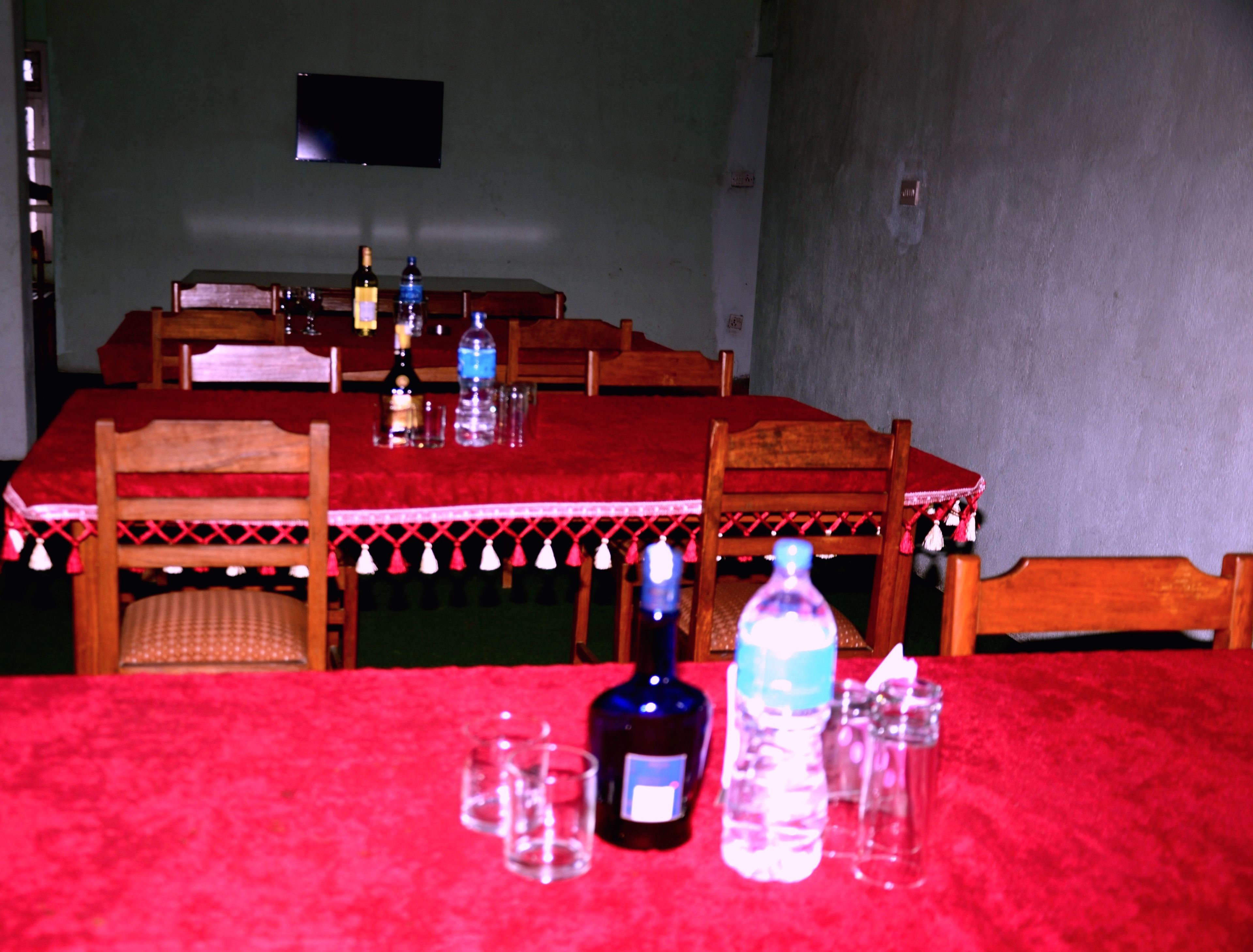 Una mesa de comedor con mantel rojo, sillas de madera y varias botellas y vasos sobre la mesa.