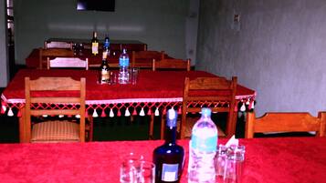 Una mesa de comedor con mantel rojo, sillas de madera y varias botellas y vasos sobre la mesa.