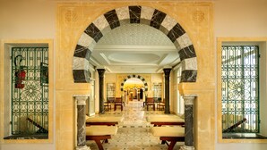 A grand hallway with a checkered floor, marble columns, and benches. - Yadis Djerba Thalasso & Golf (Djerba Midun)