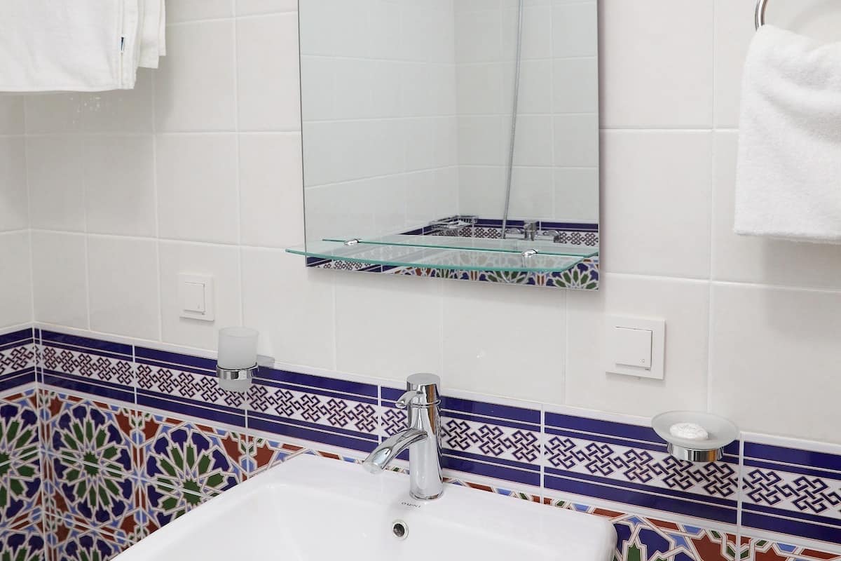 A bathroom with a white sink, a mirror, and a towel rack.