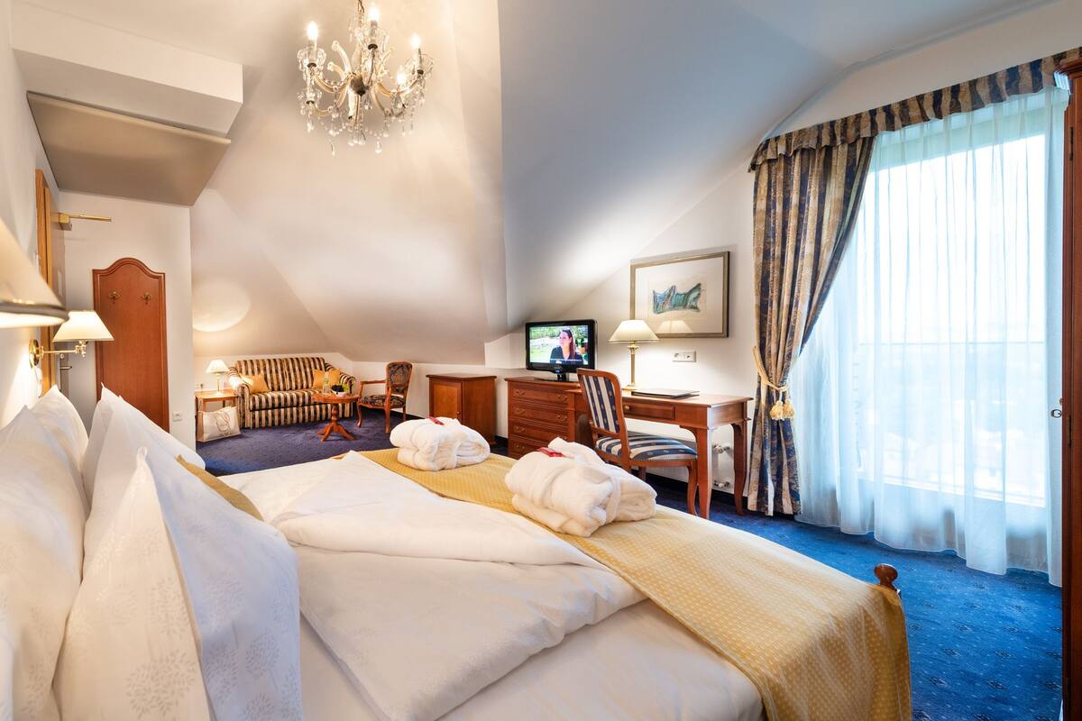 Une chambre d’hôtel avec un grand lit, un bureau, une télévision et une vue sur l’extérieur.