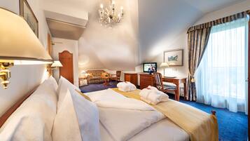 Quarto de hotel com uma cama grande, escrivaninha, televisão e vista para o exterior.