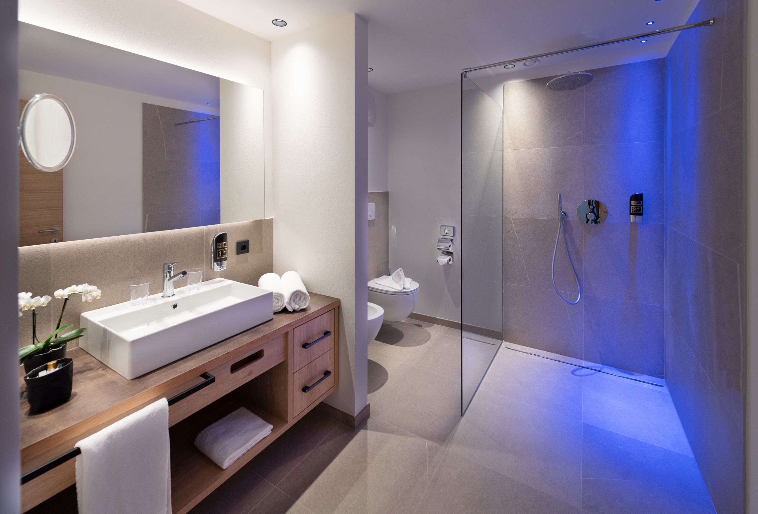 Un baño moderno con un lavamanos grande, espejo y ducha con paredes de vidrio.