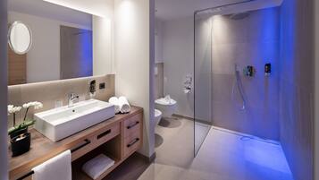 Un baño moderno con un lavamanos grande, espejo y ducha con paredes de vidrio.