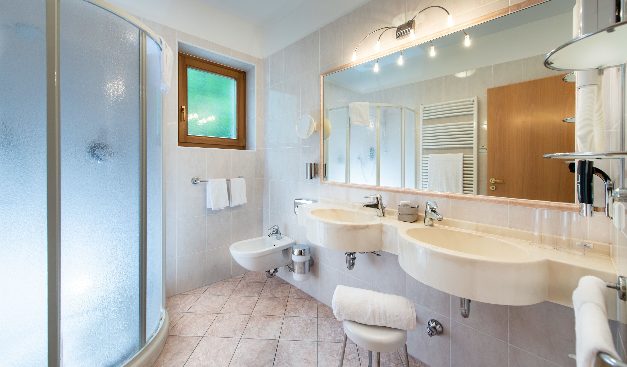 Un baño moderno con dos lavamanos, una ducha y un espejo grande.