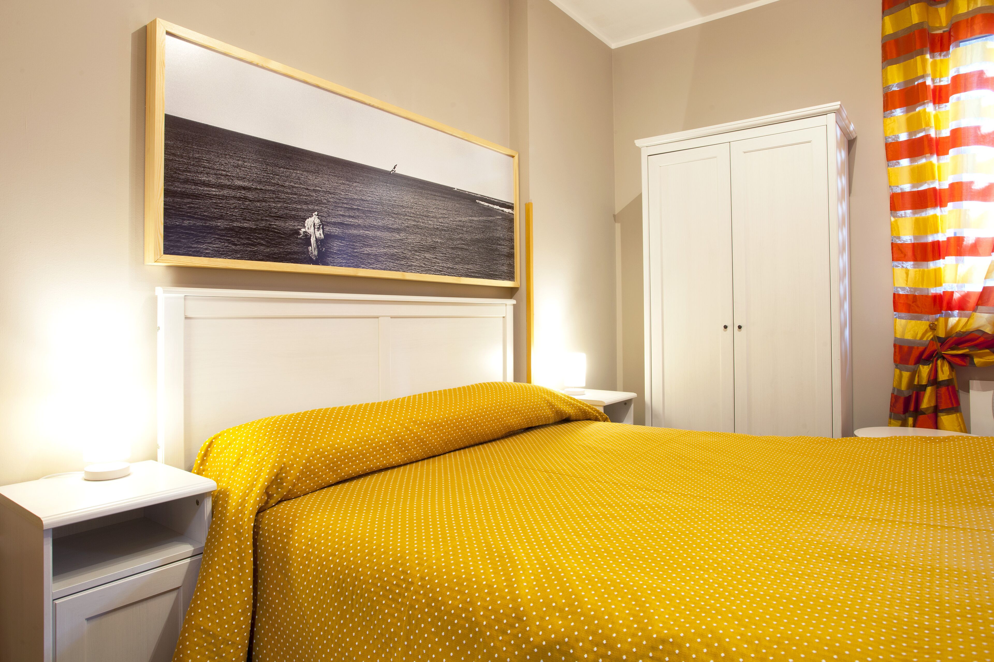 A bedroom with a bed, a nightstand, a wardrobe, and a painting on the wall.