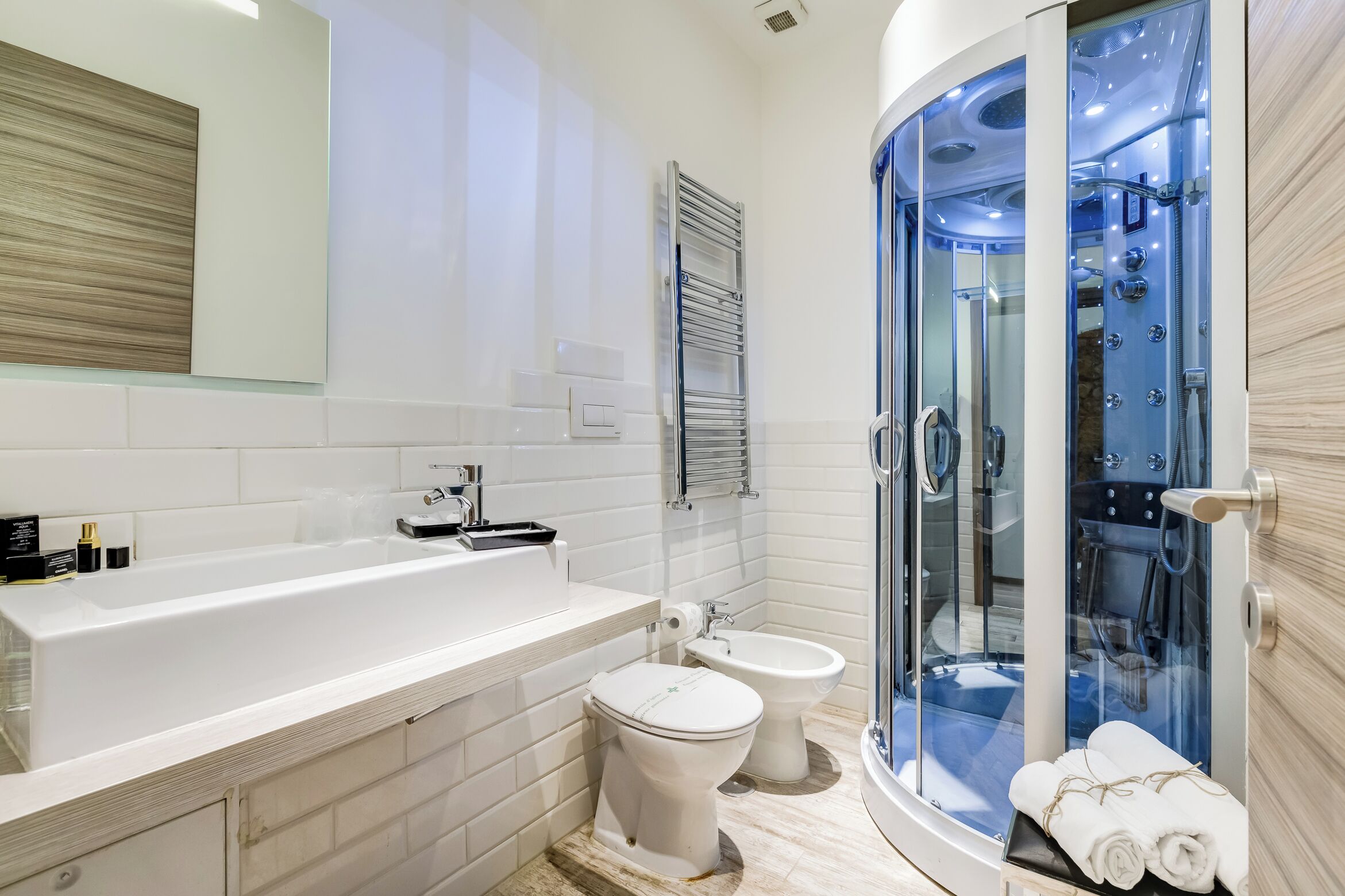 A modern bathroom with a bathtub, toilet, and a glass-enclosed shower area.