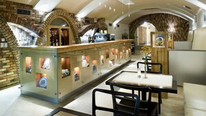 A restaurant with a stone wall, a bar area, and a dining section with tables and chairs. - Hotel Dubna Skala (Zilina)