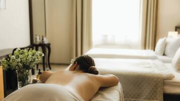 Et spa-rum med massagestol, seng og spejl.