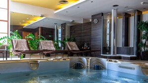 A modern indoor swimming pool with lounge chairs and a large mirror. - Hotel Dubna Skala (Zilina)