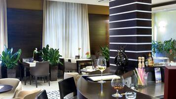 A modern hotel lobby with a curved reception desk, seating area with chairs and sofas, and decorative plants.