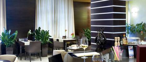 Un moderno vestíbulo de hotel con un mostrador de recepción curvo, zona de estar con sillas y sofás, y plantas decorativas.