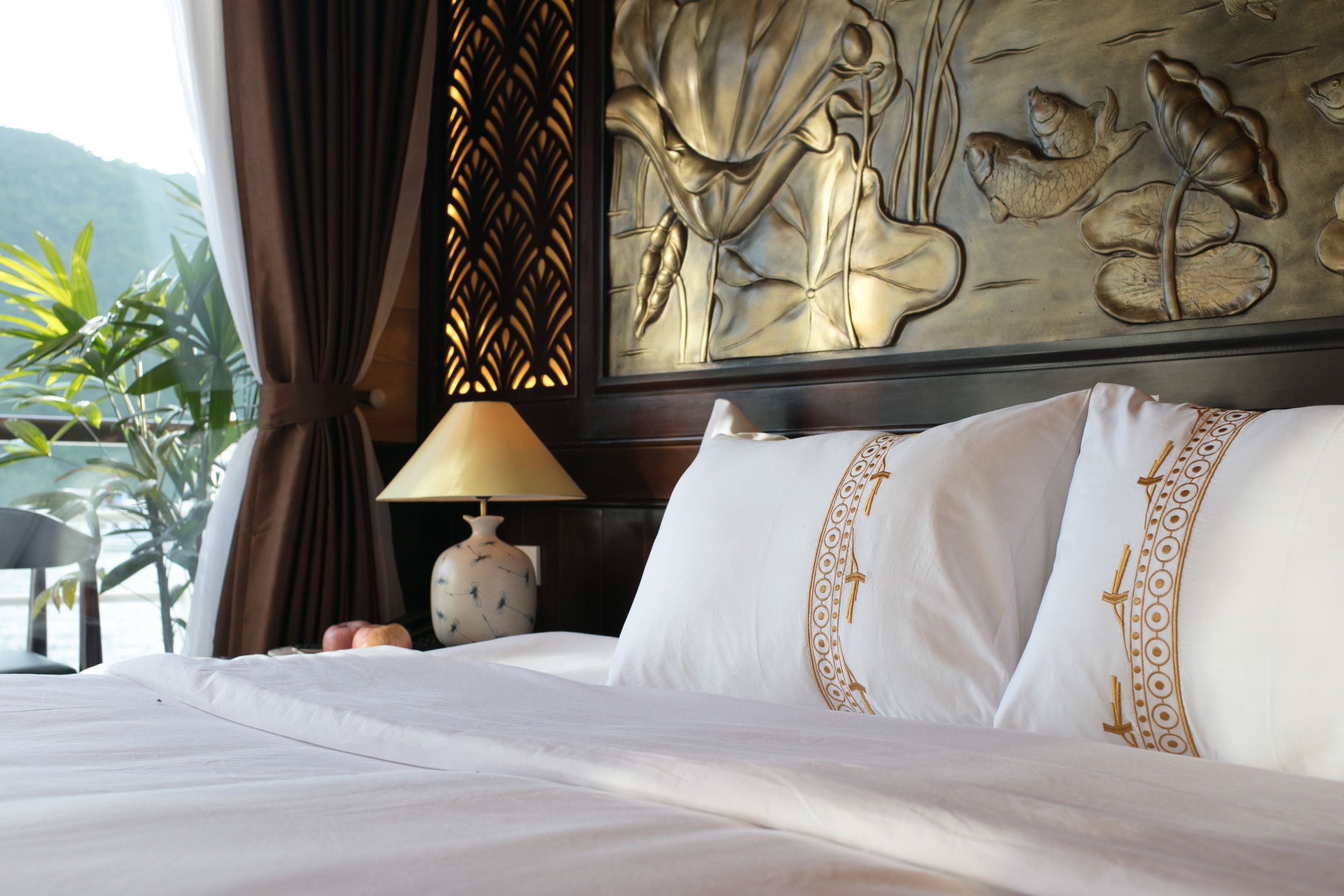 A hotel room with a bed, a lamp, and a decorative wall panel.