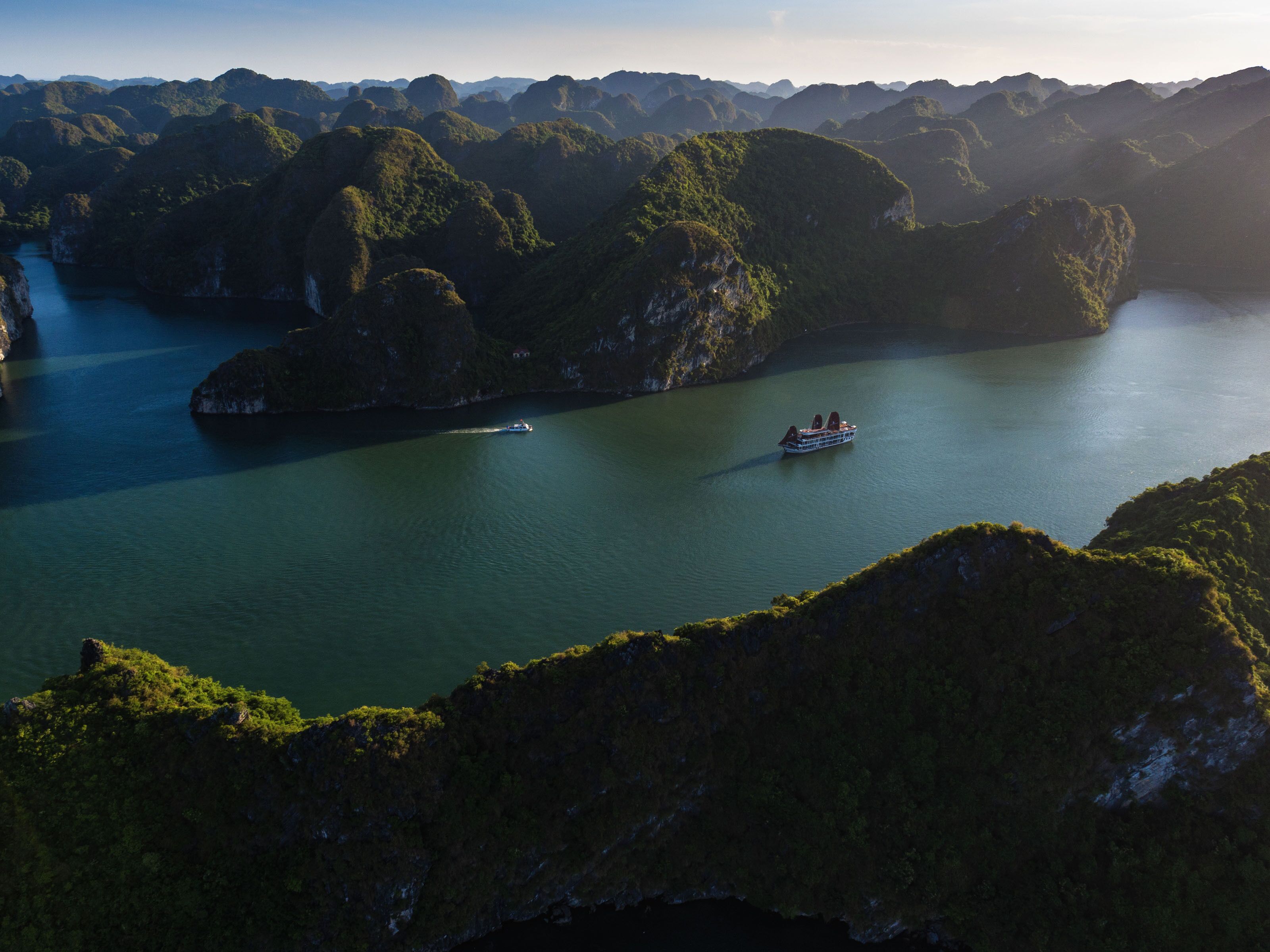 A boat on a calm river surrounded by lush green hills.