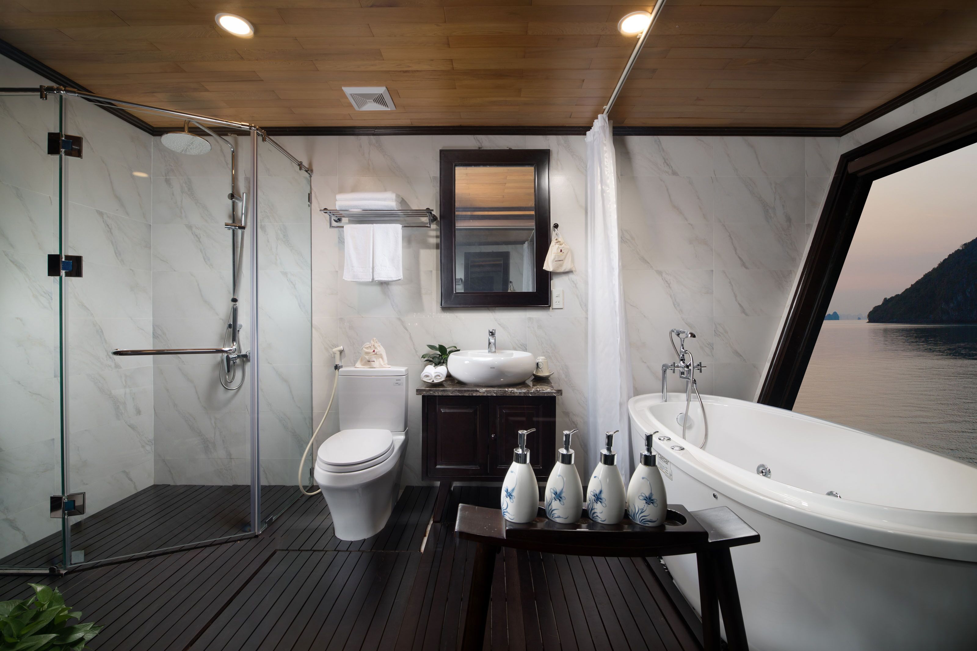 A modern bathroom with a glass-enclosed shower, a toilet, a sink, and a bathtub.