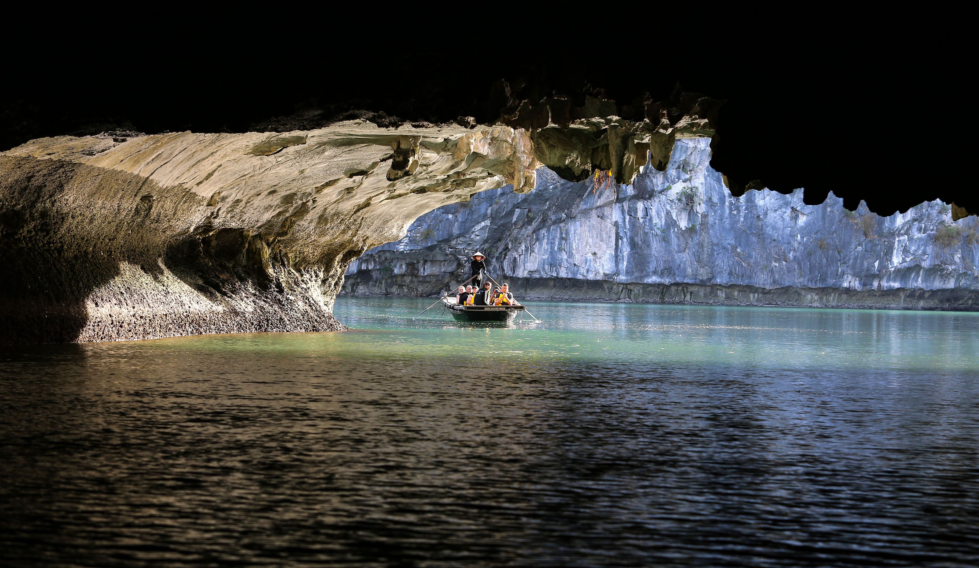 A boat with passengers near a cave entrance.