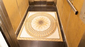 Een lift met metalen wanden en een vloer met patroon.